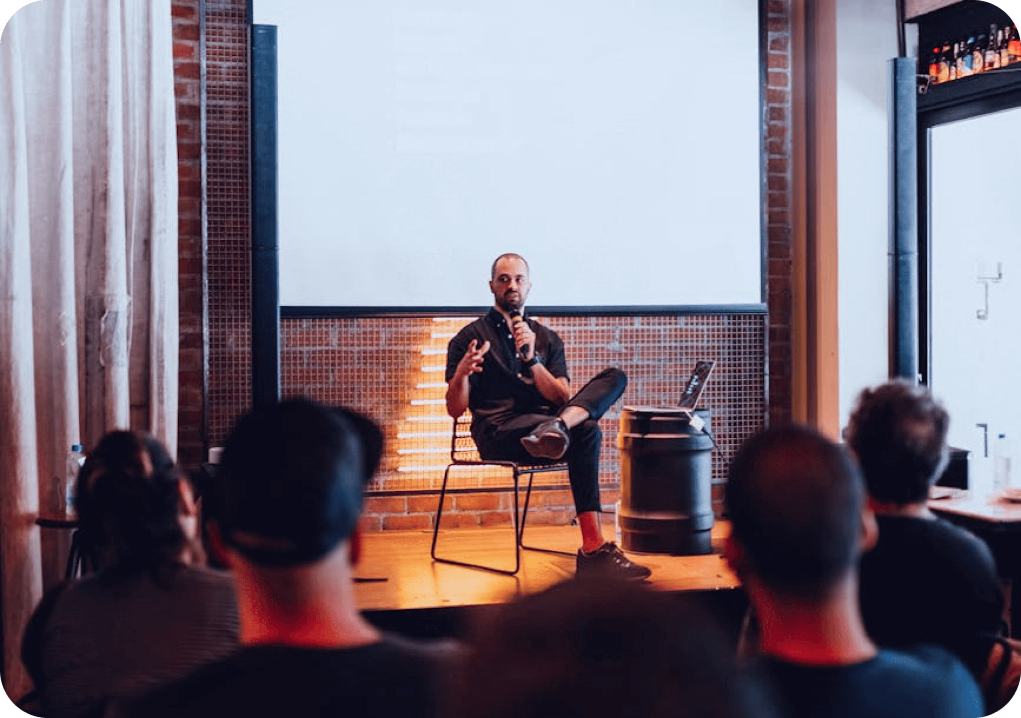 A speaker sitting on a stage with people in the audience